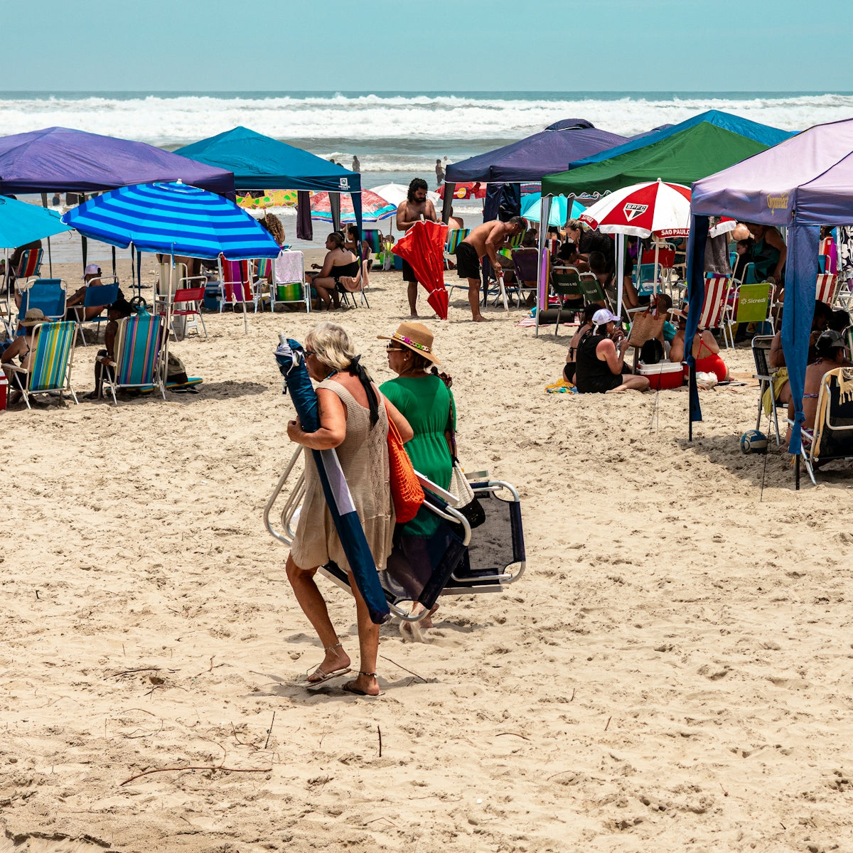 People relaxing under colorful umbrellas on a sunny beach.